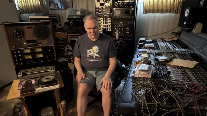 Photo of Park Peters in his recording studio.  Towards the right of the photo is a 96 channel mixer.  Towards the left of the photo and across the back wall are multiple reel-to-reel tapedecks.